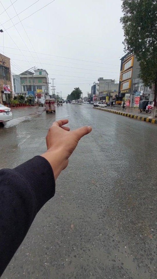 A hand reaching out over a rainy street